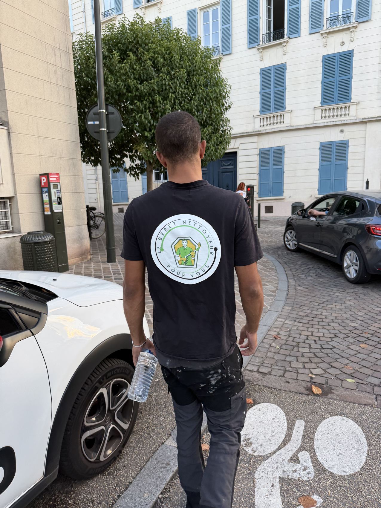 Lucas de dos dans une rue de Versailles, en tee-shirt Le Béret Nettoyeur