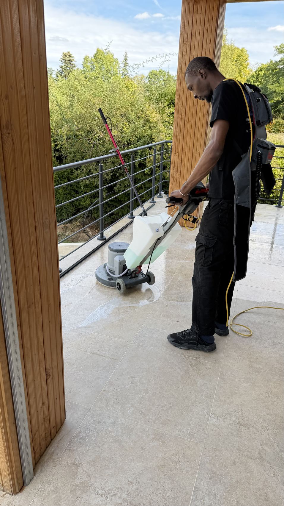 Intervenant passant la monobrosse sur une terrasse en pierre